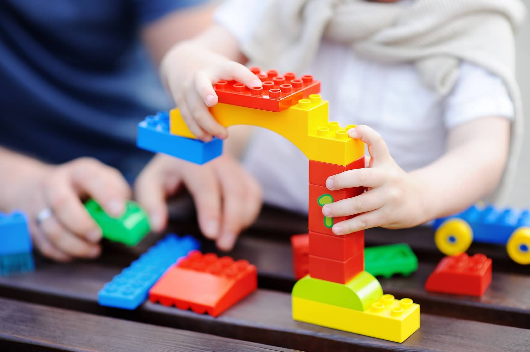 Father with his toddler son playing with colorful plastic blocks