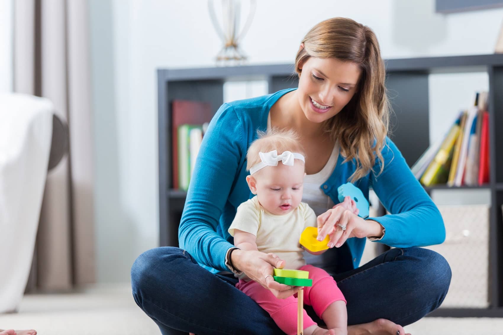 nanny plays with baby girl on the floor