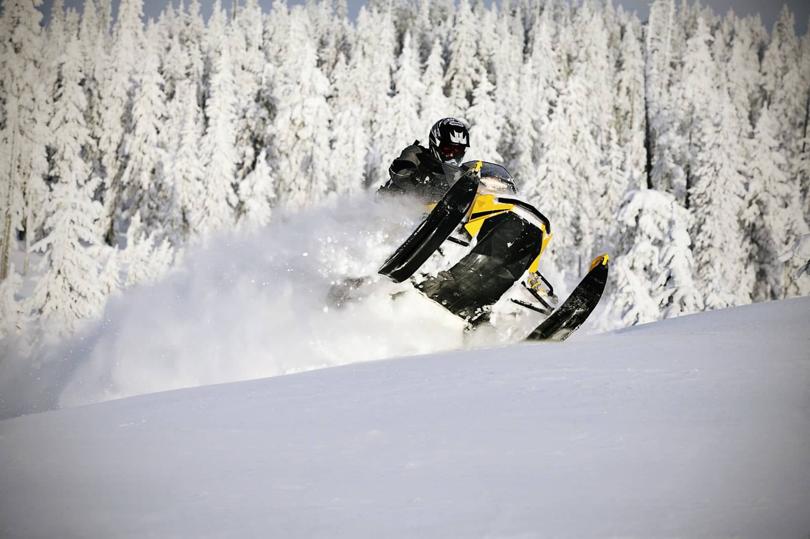 Snowmobile jumping through powdery snow